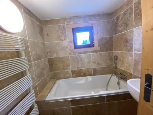 a bathroom with a tub and a sink and a window at Appartement La Clusaz, 4 pièces, 6 personnes - FR-1-459-179 in La Clusaz