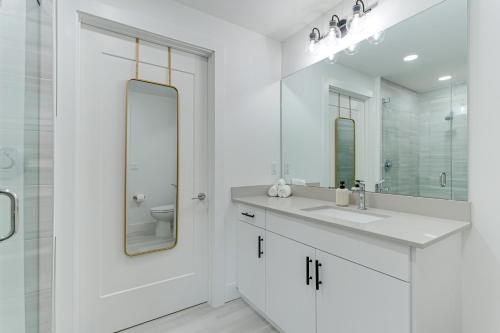 a white bathroom with a sink and a mirror at All-New, Waterfront Condo in Downtown Sarasota! in Sarasota