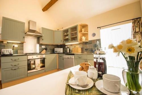 uma cozinha com uma mesa com um vaso de flores em Badgers Wood em Buxton