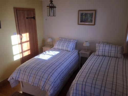 um quarto com duas camas e duas lâmpadas e uma porta em Badgers Wood em Buxton
