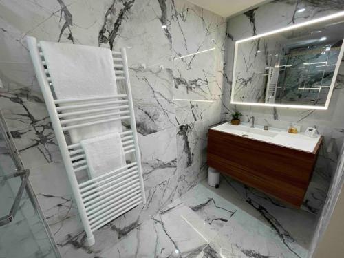 een badkamer met een witte wastafel en een marmeren muur bij Vue mer exceptionnelle, appartement unique de luxe in Cannes