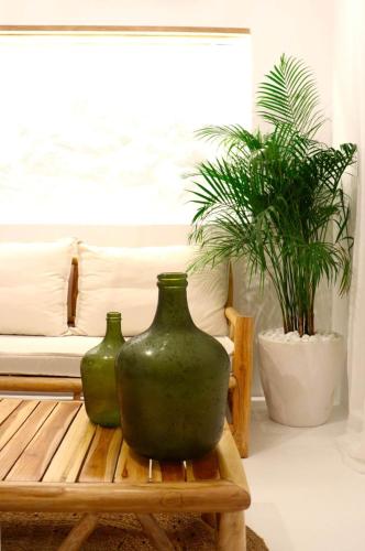 two green vases sitting on a bench in a living room at The Nine Graces - Kastraki Villas with Private Swimming Pool in Kastraki Naxou