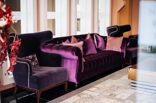 a purple couch and a chair in a room at Baron Zotel Bangkok SHA PLUS in Bangkok
