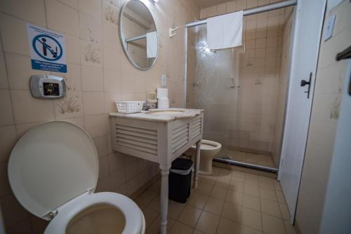 a bathroom with a toilet and a sink and a shower at Hotel Morro dos Conventos in Araranguá
