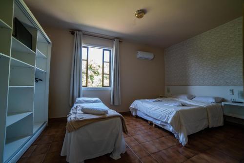 a hotel room with two beds and a window at Hotel Morro dos Conventos in Araranguá