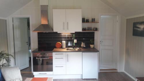 una cocina con armarios blancos y fregadero en Kleines Haus am Fjord, 