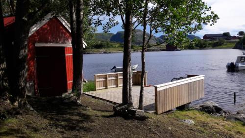 a red barn next to a dock on a lake at Kleines Haus am Fjord 