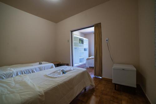 a bedroom with two beds and a door to a bathroom at Hotel Morro dos Conventos in Araranguá