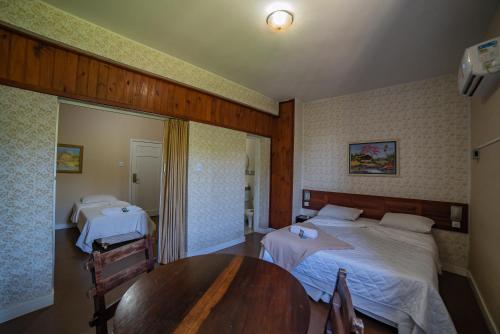 a hotel room with two beds and a table at Hotel Morro dos Conventos in Araranguá