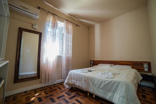 a bedroom with a bed and a window and a mirror at Hotel Morro dos Conventos in Araranguá