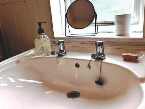 a sink in a bathroom with a mirror and a window at 'Mill Cottage' Parbold in Parbold