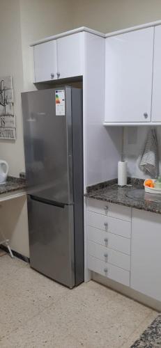 a kitchen with a stainless steel refrigerator and white cabinets at Rosyshome102 in Vecindario