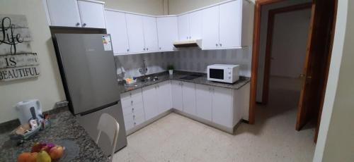 a small kitchen with white cabinets and a microwave at Rosyshome102 in Vecindario
