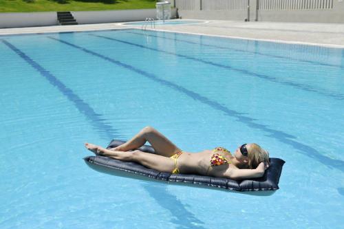 Una donna sdraiata su una zattera in una piscina di Hotel Cosmopol Cesenatico a Cesenatico