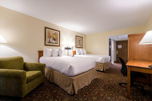 um quarto de hotel com duas camas e uma cadeira e uma secretária em Grand Vista Hotel Grand Junction em Grand Junction