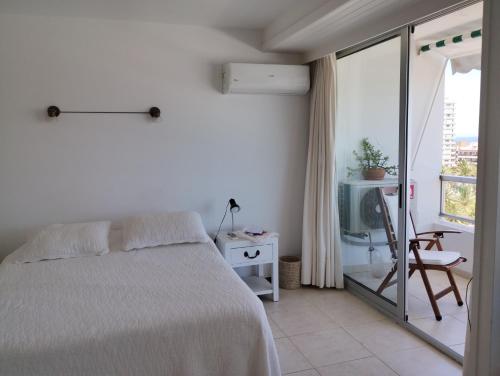 a white bedroom with a bed and a balcony at Peninsula in Punta del Este