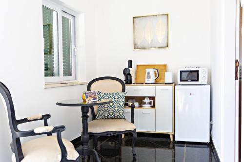 a small table and chairs in a room with a refrigerator at Suite Bela Vista in Tavira
