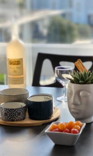 - une table avec des assiettes, des bols et une bouteille de vin dans l'établissement La Voile Bleue où il fait bon être plage et commerces à pied, au Grau-du-Roi