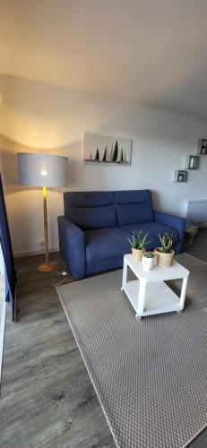 un salon avec un canapé bleu et une table dans l'établissement La Voile Bleue où il fait bon être plage et commerces à pied, au Grau-du-Roi