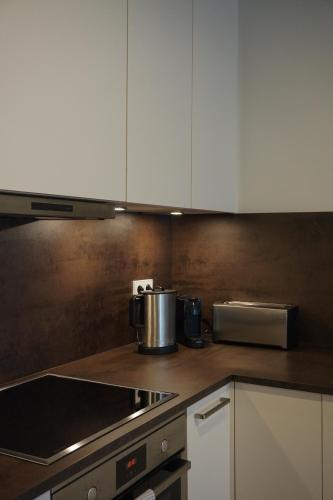 a kitchen with white cabinets and a stove top oven at Schönes Neubau Serviced-Apartment mit Parkplatz in Bruchsal