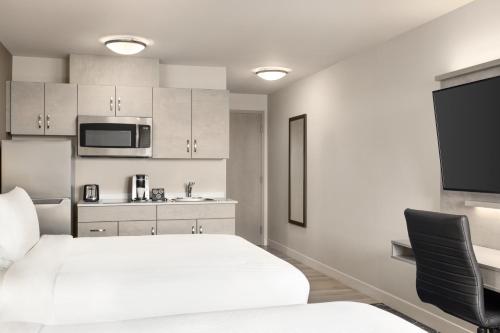 a white room with a bed and a microwave at Microtel Inn & Suites Dorval QC in Dorval