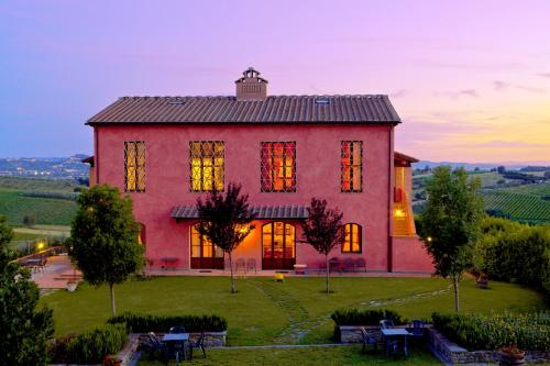 a large red house with a sunset in the background at Agriturismo Borgo Vigna Vecchia in Cerreto Guidi