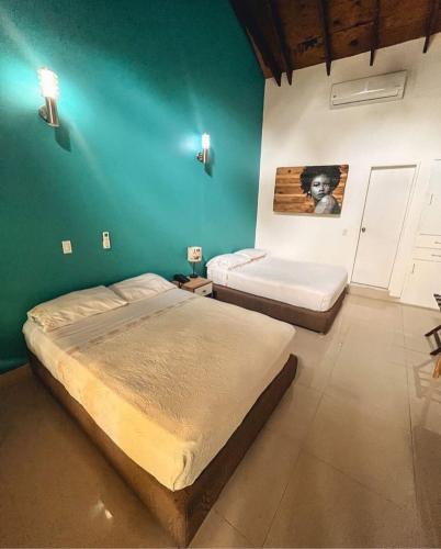 a bedroom with two beds and a green wall at Casa Las Palmas Hotel Boutique in San Andrés