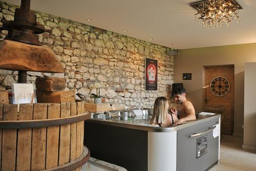 a man and a woman sitting at a counter in a kitchen at Les Insolites du Domaine de Suzel in Vignieu