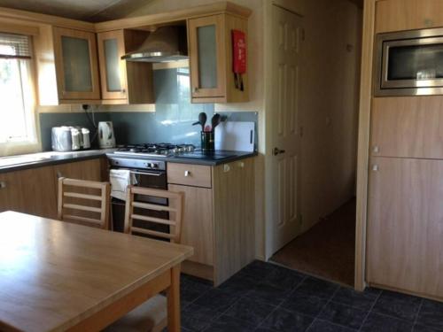 a kitchen with wooden cabinets and a wooden table with a tableablish at Static Caravan (Cliburn Station) in Penrith