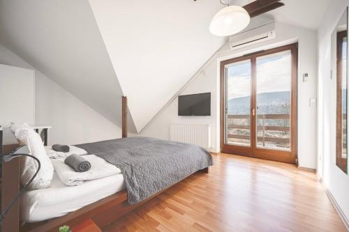 a white bedroom with a bed and a large window at Panorama Buda in Budapest