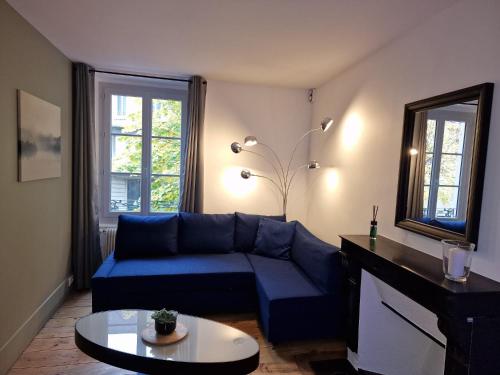 a living room with a blue couch and a mirror at Appartement 2/4 pers Le Cosy in Lons-le-Saunier