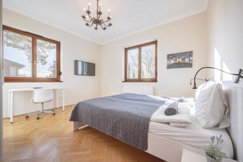 a white bedroom with a bed and a desk at Panorama Buda in Budapest