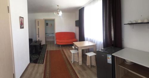 ein Wohnzimmer mit einem roten Stuhl und einem Tisch in der Unterkunft Пансионат "Скиф-Мурок" in Bosteri