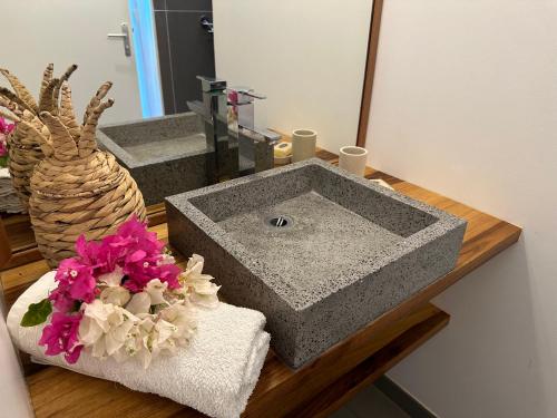 La salle de bains est pourvue d'un lavabo et de fleurs sur un comptoir. dans l'établissement EAST KEYS - Lucy's Bay, à Hyacinthe