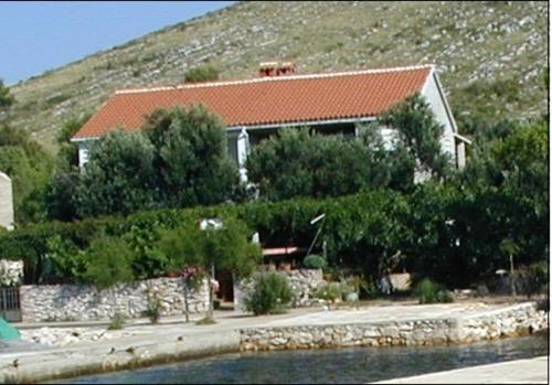 a house on a hill next to a body of water at Apartments & Stone cottage - National park Kornati in Vala
