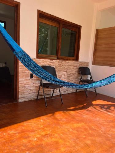 two chairs and a hammock in a room at Cabañas las Palmas Chacahua in Yegüey