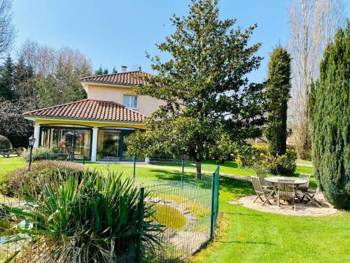 a house with a fence and a table in a yard at Les Villas du Domaine de Suzel in Vignieu
