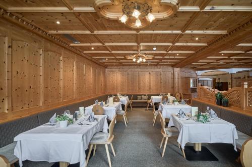 a restaurant with white tables and chairs and a chandelier at Wellness-Sporthotel Ratschings in Racines