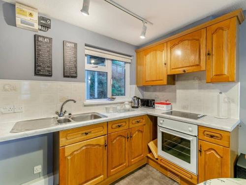 a kitchen with wooden cabinets and a sink at Sand Bar - Mount Brioni in Downderry