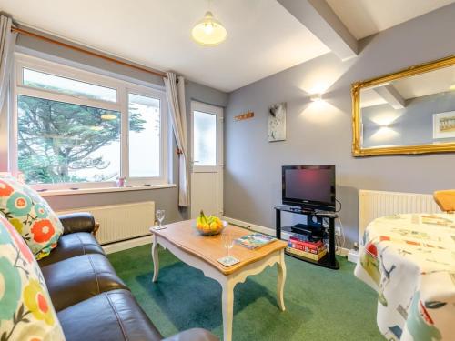 a living room with a couch and a table and a tv at Sand Bar - Mount Brioni in Downderry