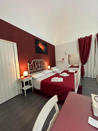 una habitación de hotel con una cama grande y una pared roja en Etna Rooms en Catania