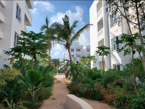 a pathway with palm trees and plants in front of a building at Modern Apartment - Work from Zanzibar (Fumba Town) in Dambani
