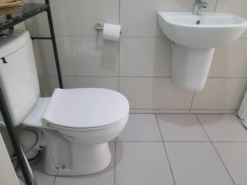 a white bathroom with a toilet and a sink at Modern Apartment - Work from Zanzibar (Fumba Town) in Dambani