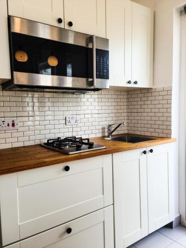 a kitchen with white cabinets and a sink and a microwave at Modern Apartment - Work from Zanzibar (Fumba Town) in Dambani