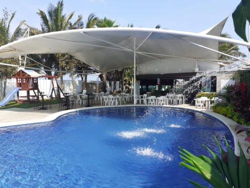 a large swimming pool with a white umbrella at Hotel La Estrella Polar in Costa Esmeralda