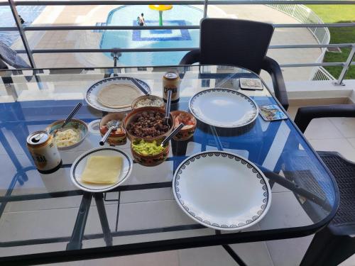 a glass table with plates of food on it at Hermoso apartamento con piscina (alberca). in Girardot