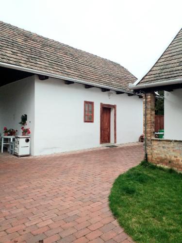 a white house with a brick driveway at Pipacs és Tulipán Vendégház in Bodony