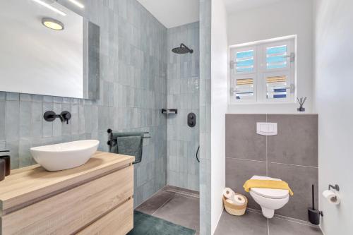 La salle de bains est pourvue d'un lavabo, de toilettes et d'une douche. dans l'établissement Brand new Two Bedroom Apartment at the Water, à Kralendijk