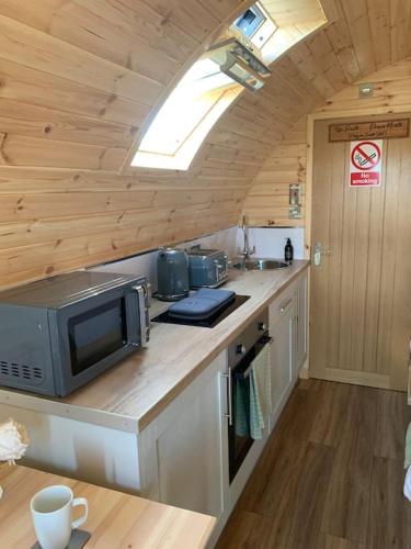 a kitchen with a counter with a microwave and a sink at Loch an Eilean Pod Isle of South Uist in Pollachar