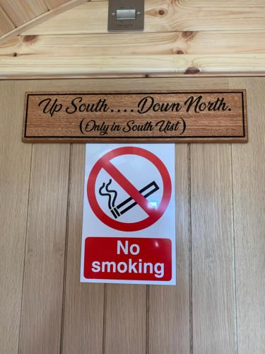 a sign on a wooden door with a no smoking sign at Loch an Eilean Pod Isle of South Uist in Pollachar